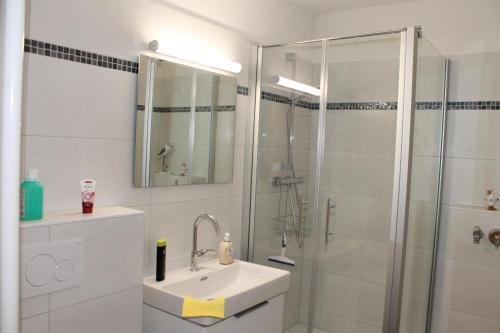 a white bathroom with a shower and a sink at Ostseeappartement K014 in Brasilien