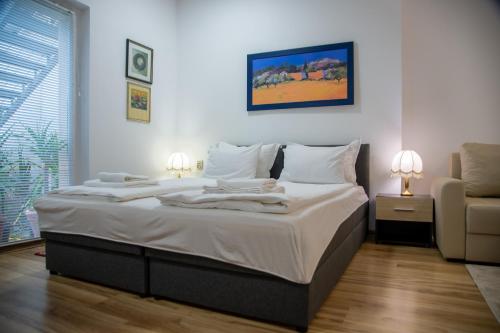 a bedroom with a large bed with white sheets at Apartman Centar in Sremski Karlovci