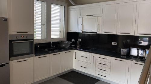 a kitchen with white cabinets and black counter tops at Sunset Bay Villa at Gjiri Lalzit Durres in Durrës