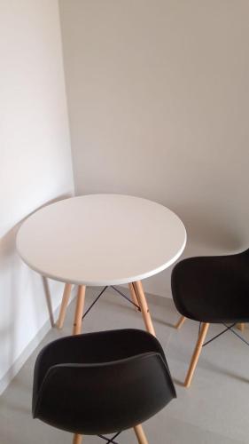 uma mesa branca e duas cadeiras pretas num quarto em Flat mobiliada em Sinop
