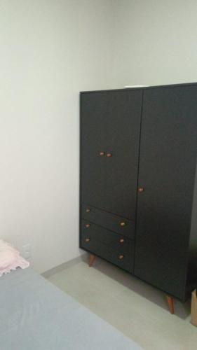 uma cómoda preta num quarto com uma cama em Flat mobiliada em Sinop