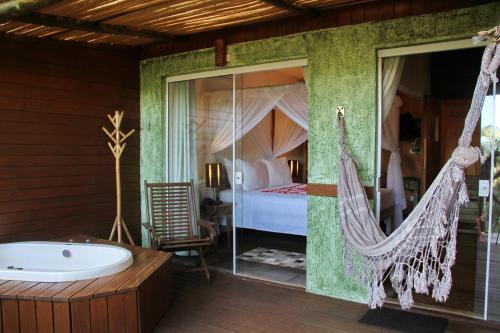 a bedroom with a hammock and a bed and a tub at Ilha de Toque Toque Eco Hotel in São Sebastião