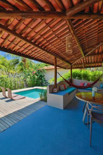 a patio with a table and a hammock and a pool at Villas Taturé in São Miguel dos Milagres