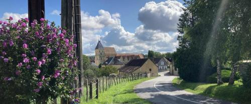 una carretera en un pueblo con una iglesia y flores púrpuras en Le refuge, en Ceton