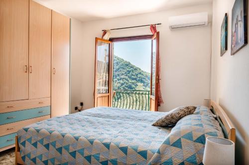 een slaapkamer met een bed en een groot raam bij Turri House--- WiFi -Garden-Parking -Balcony in Recco