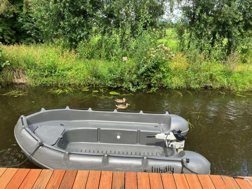 a small boat on the water next to a dock at Oasis holiday home in Giethoorn next to canal, boat extra in Giethoorn