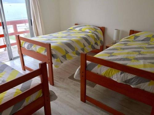 two twin beds in a room with a window at Casa de dos pisos a pasos de la playa in Bahia Inglesa