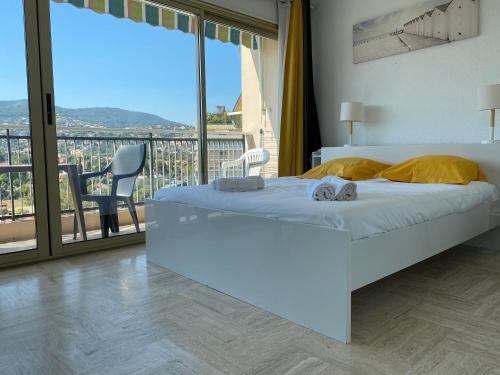 a bedroom with a white bed and a balcony at Studio Cannes Marina Mandelieu in Mandelieu-la-Napoule