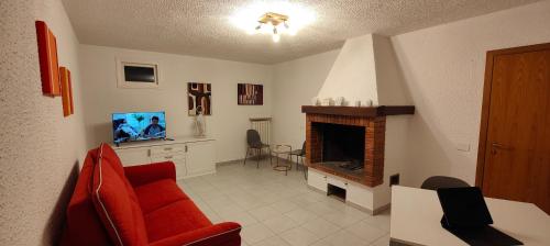 een woonkamer met een rode bank en een open haard bij Case Gioto e Bellavista in Passignano sul Trasimeno