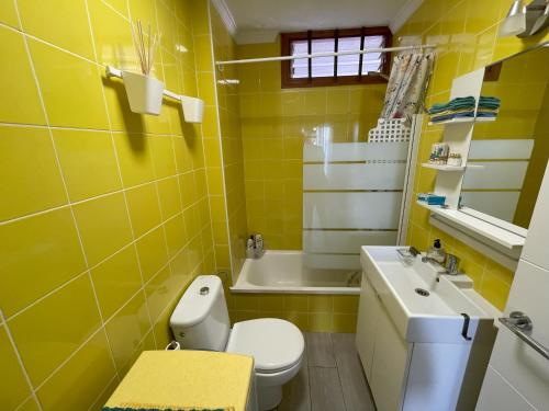 bagno giallo con servizi igienici e lavandino di Fine Art Jeans Apartment ad Arona