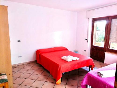 a room with a red bed with a red blanket at Villa Simone (Cagliari, Escalaplano, Sardegna) 