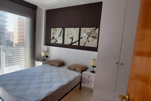 ein Schlafzimmer mit einem Bett mit drei Gemälden an der Wand in der Unterkunft Bravaholidays-295-Central Park in Blanes