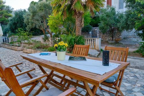a wooden table with three chairs and a table with flowers at Apartment Pepermint - near Ljubicic Tennis Academy in Veli Lošinj
