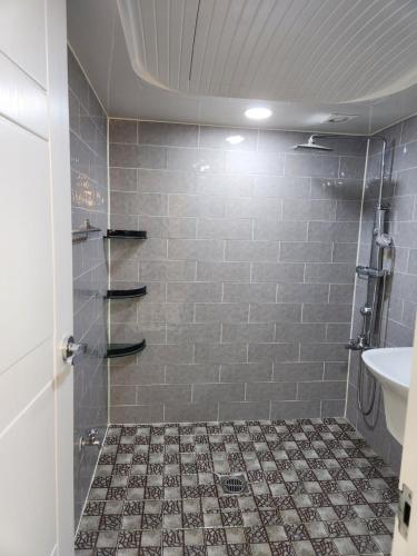 a bathroom with a shower with a tiled floor at Urbanspace Pohang in Pohang