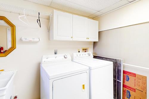 - une buanderie avec des armoires blanches et un lave-linge/sèche-linge dans l'établissement High Country Cottage, à Newland