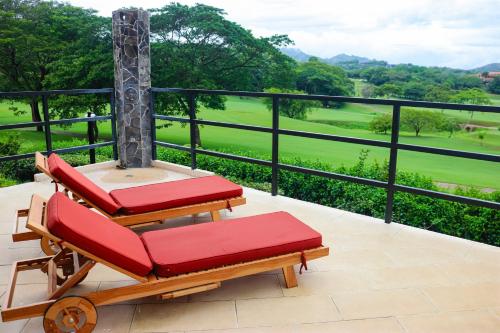 two red lounge chairs on a balcony with a view at Bougainvillea 2101 in Playa Conchal