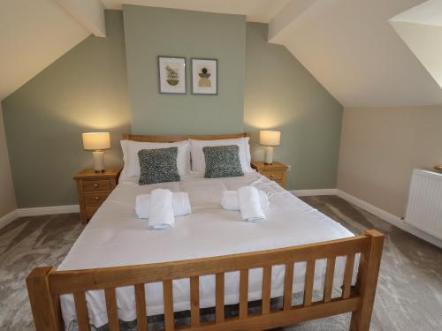 a bedroom with a large white bed with two lamps at Rhos Las in Derwen