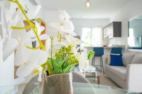 a vase with white flowers sitting on a table in a living room at Playa Palmera Beach Resort in Punta Cana