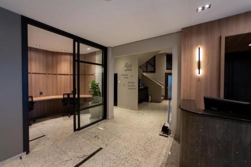 un vestíbulo de oficina con una gran puerta de cristal y una escalera en Luz Hotel Pato Branco, en Pato Branco