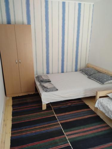 a small room with a bed and a striped wall at Втори километър in Ovcha Mogila