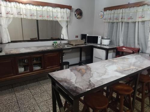 a kitchen with a counter and a table with stools at Casa de campo en Río Cuarto in Río Cuarto
