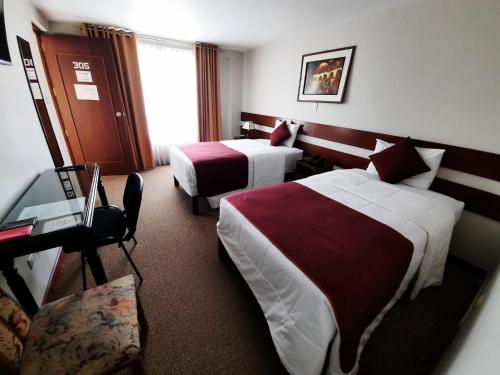 a hotel room with two beds and a desk at Bella AQP in Arequipa