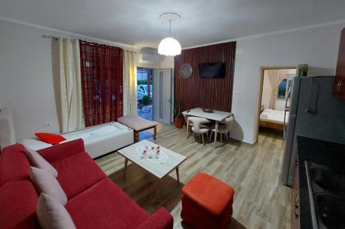 villa Heljos apartaments في فلوره: غرفة معيشة مع أريكة حمراء وطاولة