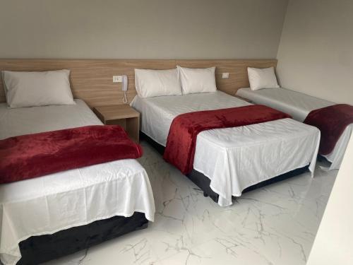 a room with three beds with red blankets at Hotel Fênix Belenzinho in Sao Paulo