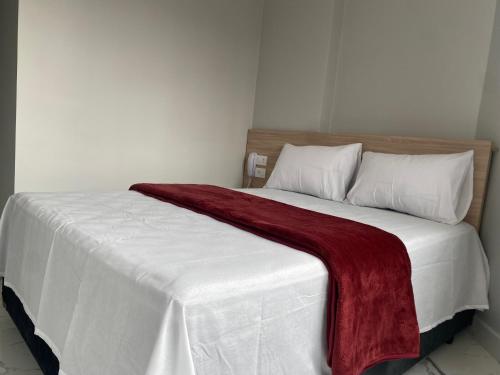a large white bed with a red blanket on it at Hotel Fênix Belenzinho in Sao Paulo