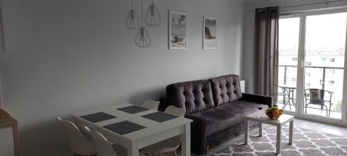a living room with a couch and a table at Baltea Sunrise Apartment - blisko Parku Reagana i plaży in Gdańsk