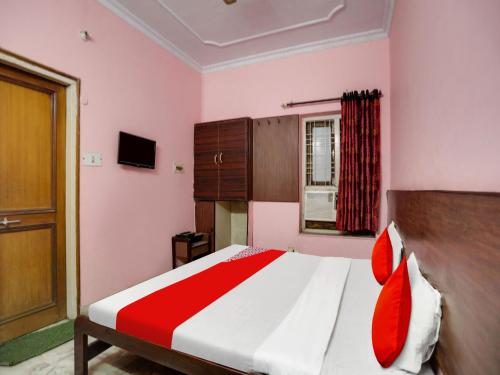 a bedroom with pink walls and a bed with red pillows at OYO Flagship Jaiswal Star Stay in Lucknow