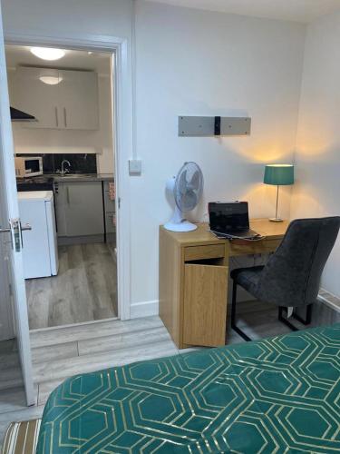 a room with a desk and a chair and a kitchen at Oak Lodge in Welling