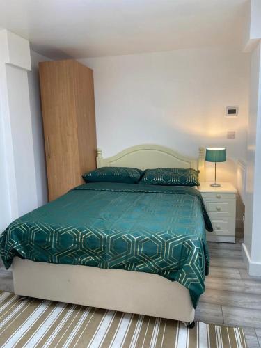 Oak Lodge في Welling: غرفة نوم مع سرير مع لحاف أخضر