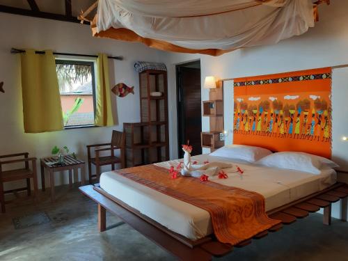 a bedroom with a large bed with an orange headboard at Libertalia Hotel in Sainte Marie