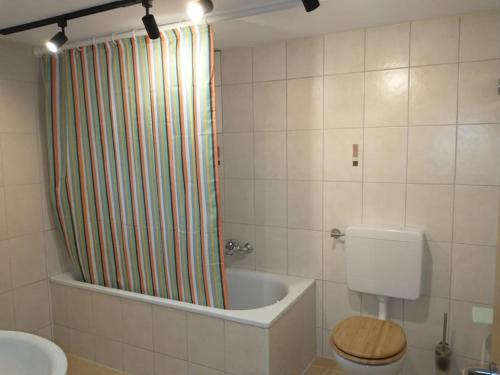La salle de bains est pourvue d'une baignoire, de toilettes et d'un rideau de douche. dans l'établissement Schicke hundefreundliche Wohnung, à Alsheim