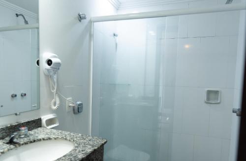 a shower with a glass door next to a sink at San Rafael Comfort Class Hotel in Foz do Iguaçu