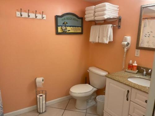 a bathroom with a toilet and a sink and a mirror at Nw Condo Steps To Beach Overlooking Pool & Ocean in North Wildwood