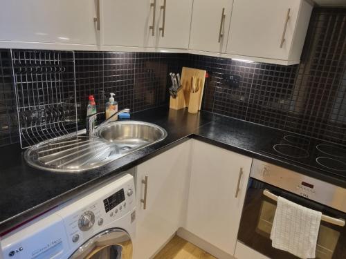 a kitchen counter with a sink and a dishwasher at Stunning 2 Bed/2 Bath Flat in Waterloo, London in London