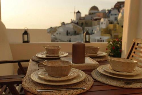 a wooden table with cups and plates on a table with a view at οικογενειακό διαμέρισμα στην Οία in Oia