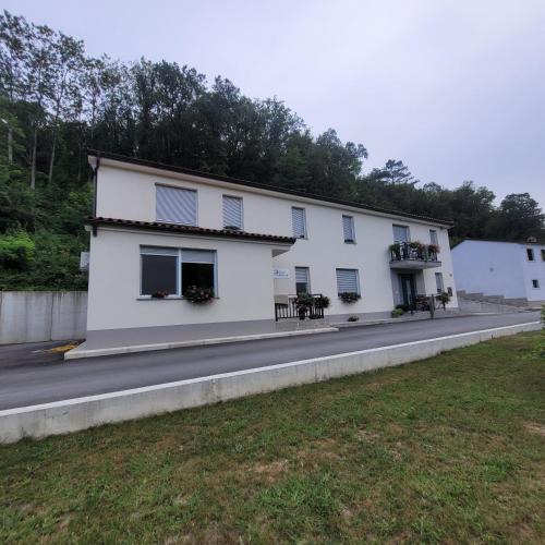 a white building with windows on the side of a road at Apartma Uhanje pri Božičevih in Ajdovščina