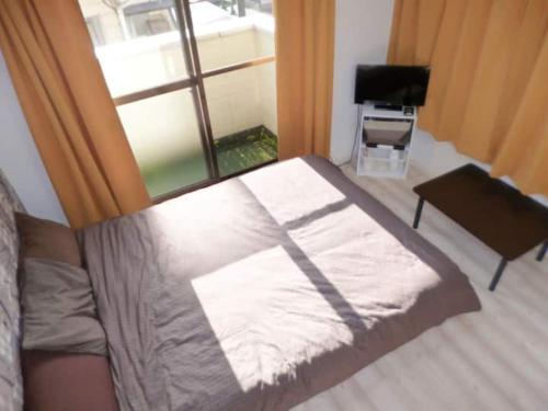 a bed sitting in a room with a window at The Mickey Carlton Ohashi Alpha Coat - Vacation STAY 15164 in Fukuoka