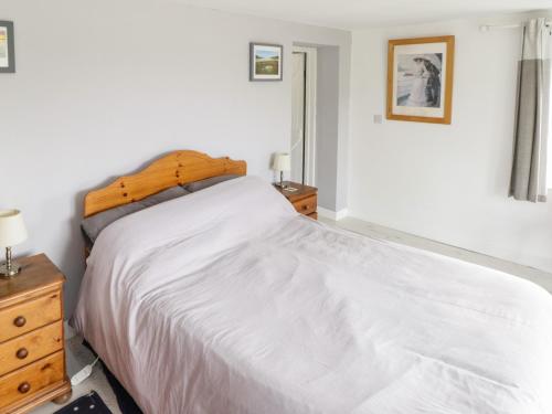 a bedroom with a large white bed with a wooden headboard at Sound Cottage in Sraheens