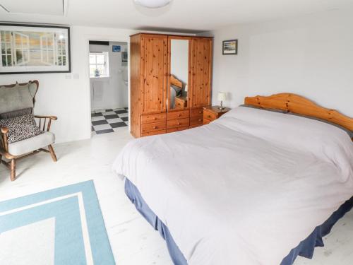 a bedroom with a large bed and a chair at Sound Cottage in Sraheens