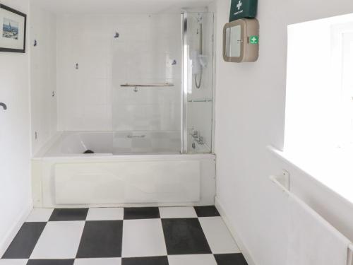 La salle de bains est pourvue d'une baignoire et d'un sol en damier. dans l'établissement Sound Cottage, à Sraheens