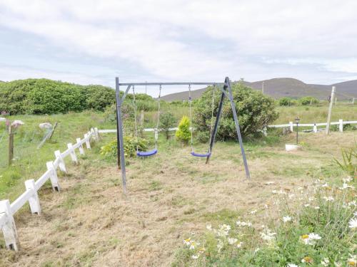 a playground in a field with two swings at Sound Cottage in Sraheens