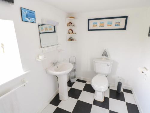 a bathroom with a white toilet and a sink at Sound Cottage in Sraheens
