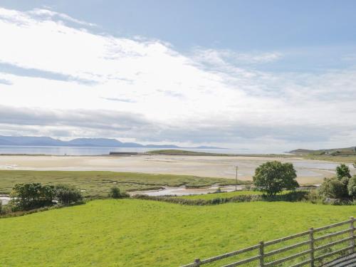 a view of the beach from a hill with a fence at Sound Cottage in Sraheens