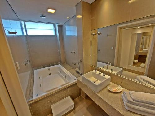 a bathroom with a tub and a sink and a mirror at Garanhuns Palace Hotel in Garanhuns