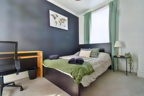 a bedroom with a bed and a desk and a window at Central Exeter's Perfect 2 BR Flat in Exeter