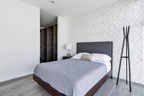 a bedroom with a large bed and a white wall at Departamento elegante en Querétaro in Miranda